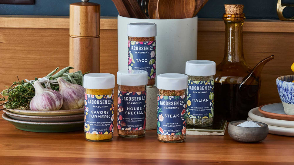 Jacobson's Salt Co. seasoning jars on a wooden surface with kitchen items in the background