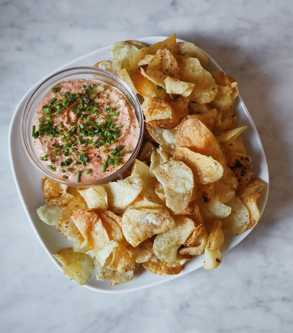 Plate with seasoned potato chips and dip topped with chives.