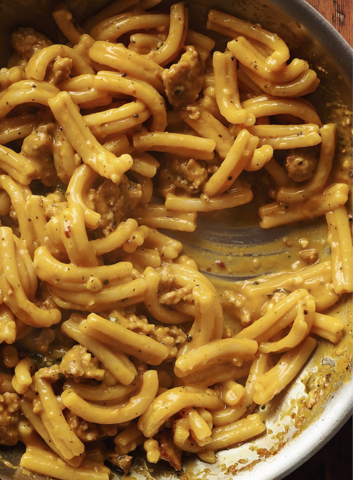 Closeup of yellow pasta on stovetop pan.