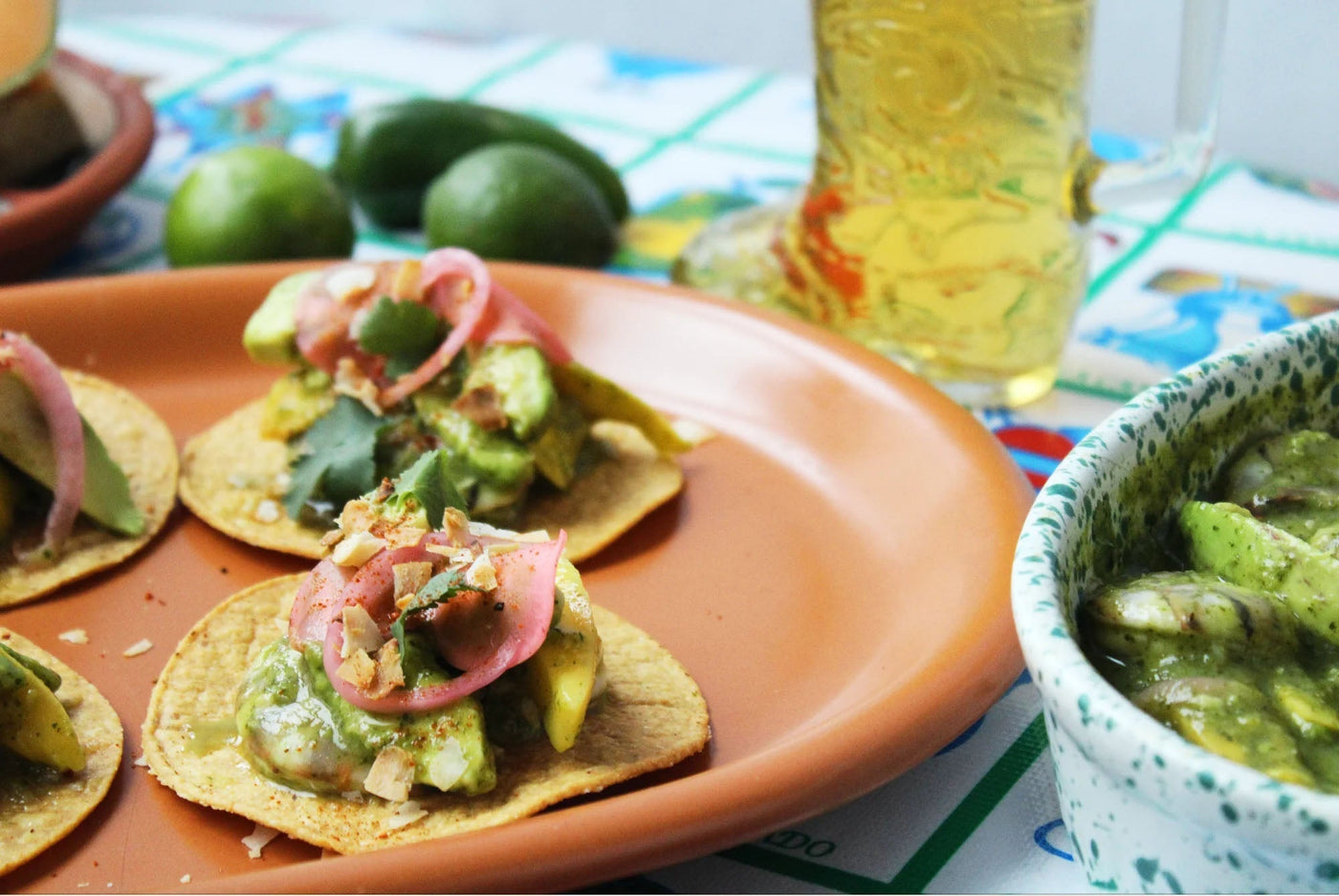 A plate of four ceviche tostadas sits atop a decorative tiled table.