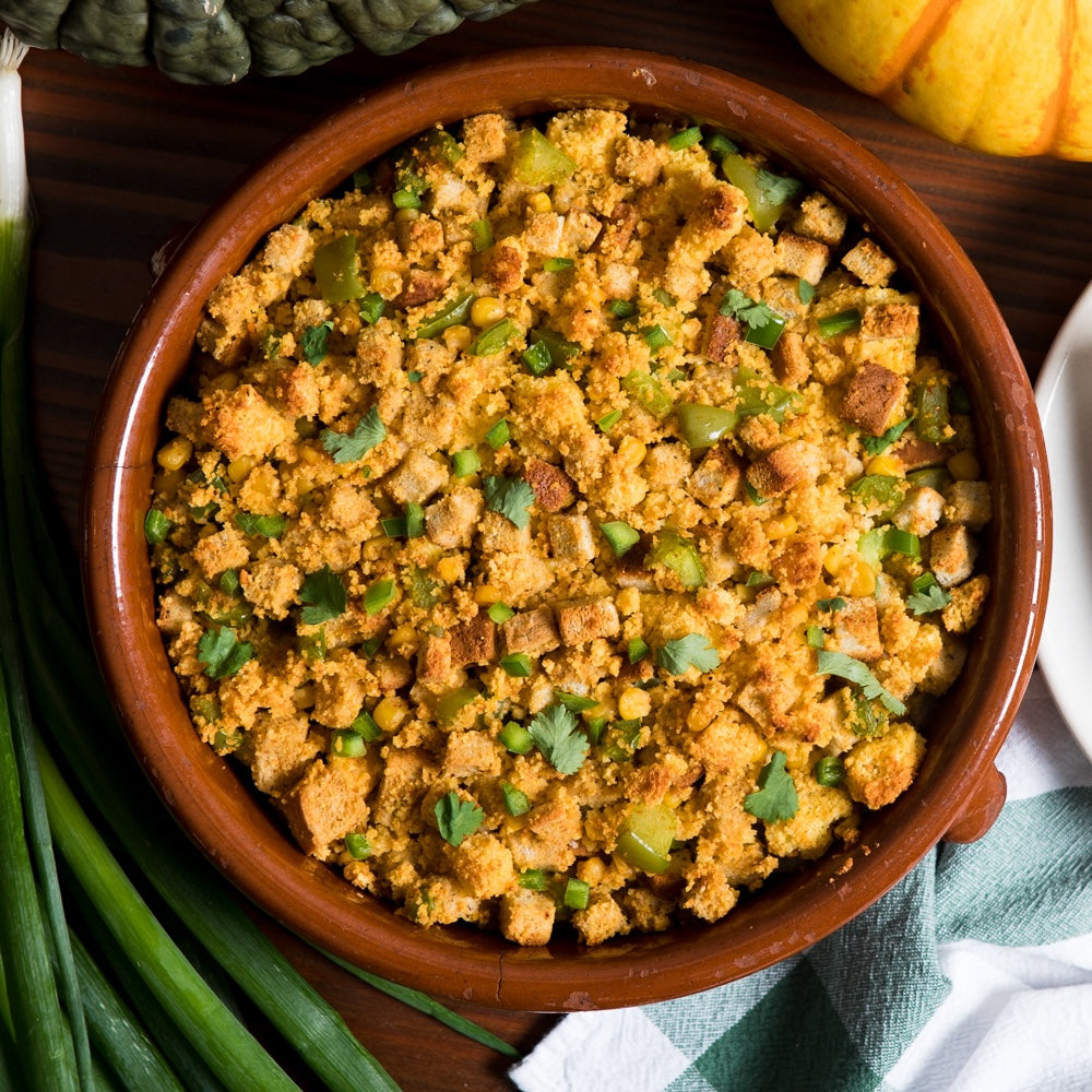 A bowl with southwestern cornbread stuffing, topped with green herbs.