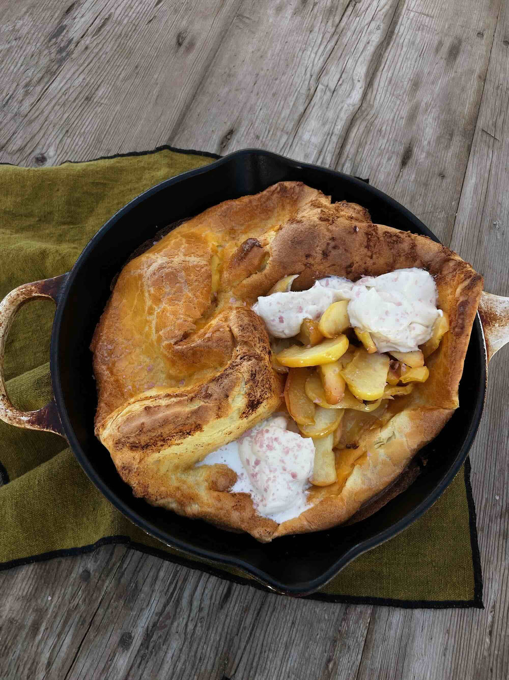 Dutch baby breakfast in skillet, on rustic wooden table.