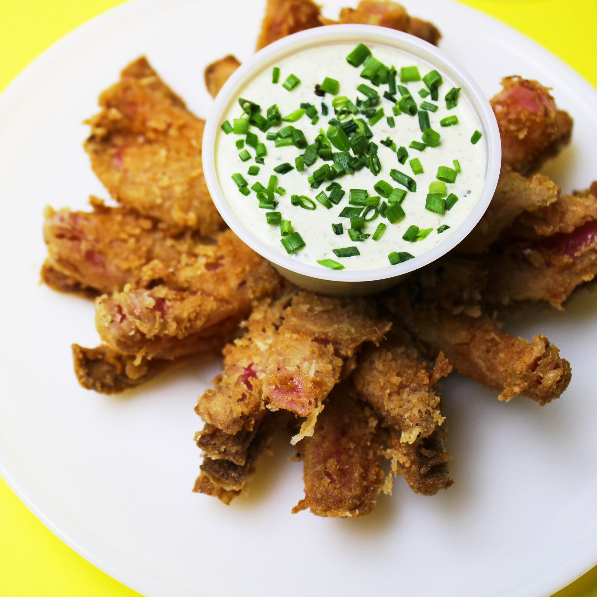 A fried onion bloom with a bowl of dipping sauce.