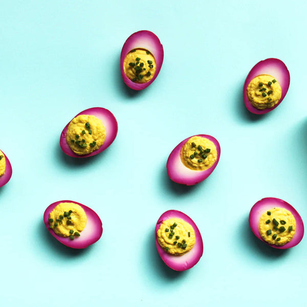 Seven purple deviled eggs on a light blue background.