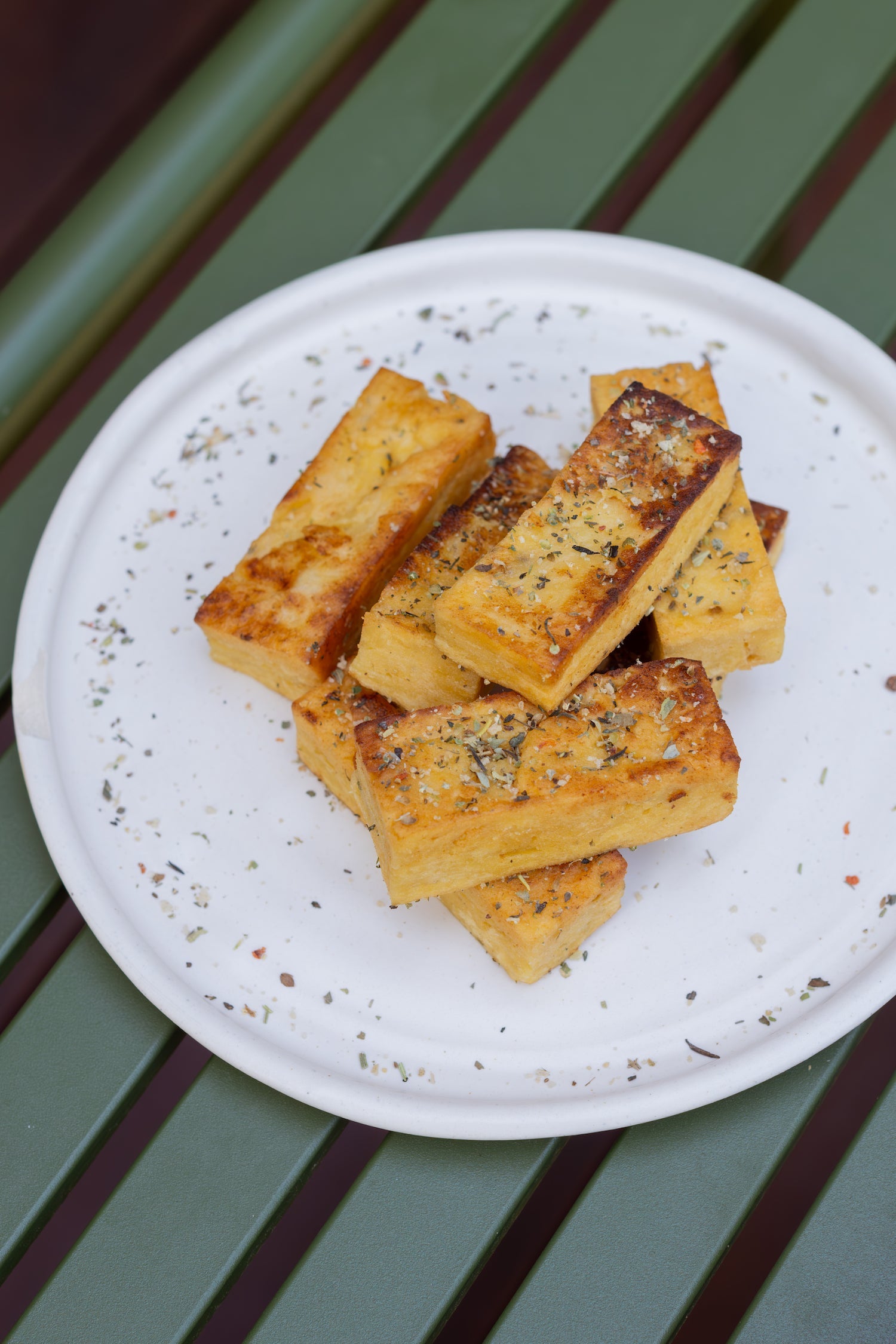 Several pieces of fried tofu on a white plate. 