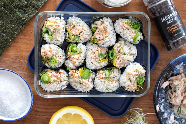 A glass Tupperware filled with slices of salmon kimbap.
