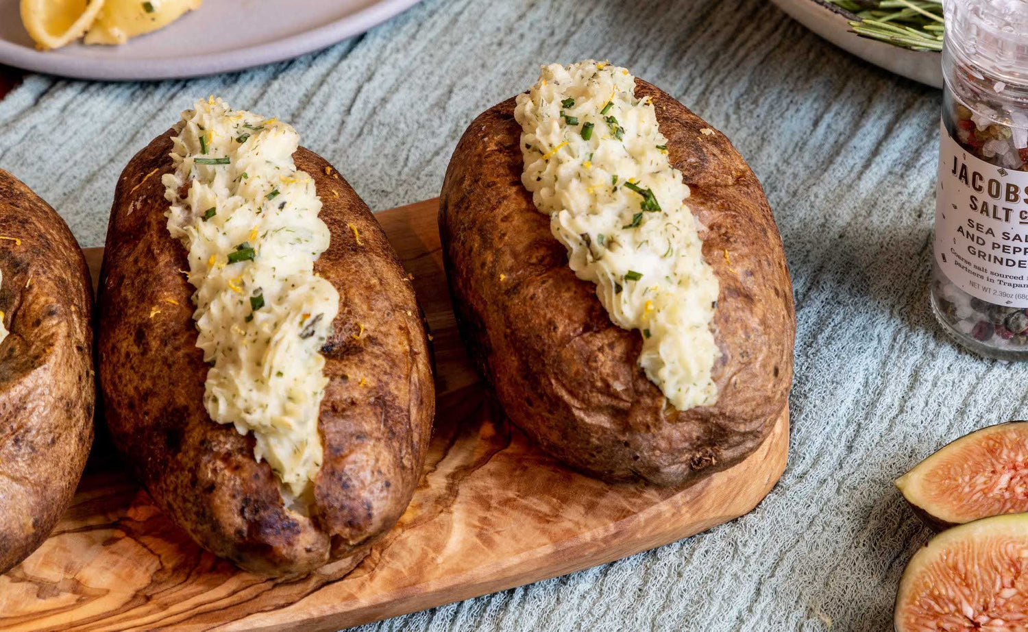 Two twice baked potatoes on a wooden cutting board.