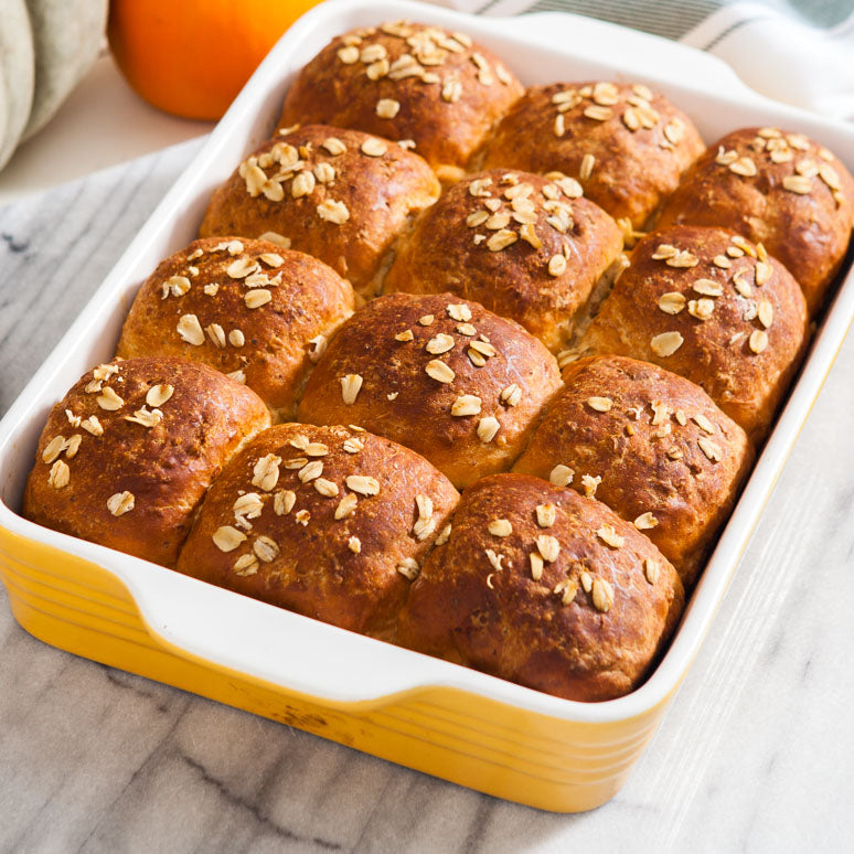 A baking dish with twelve dinner rolls.