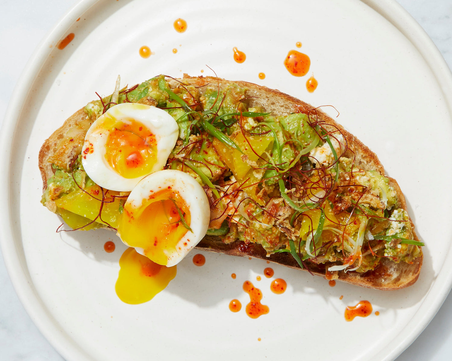 A slice of toast with avocado and a soft boiled egg.