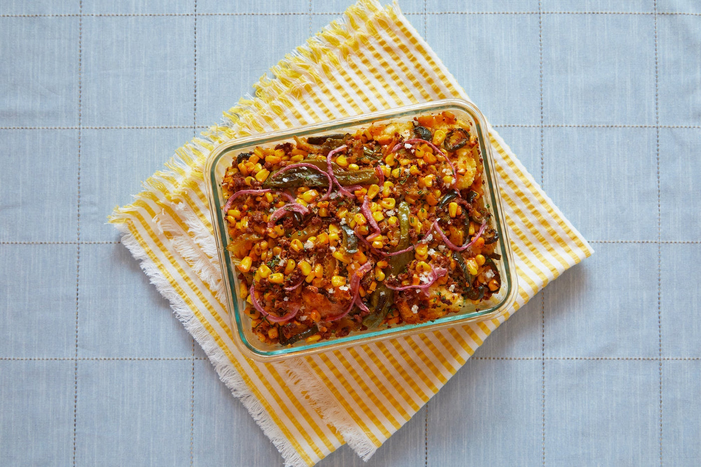 A baking pan of cornbread stuffing sits on top of a striped yellow towel.