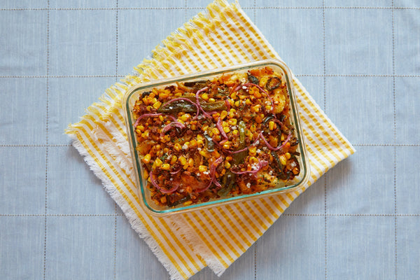 A baking pan of cornbread stuffing sits on top of a striped yellow towel.