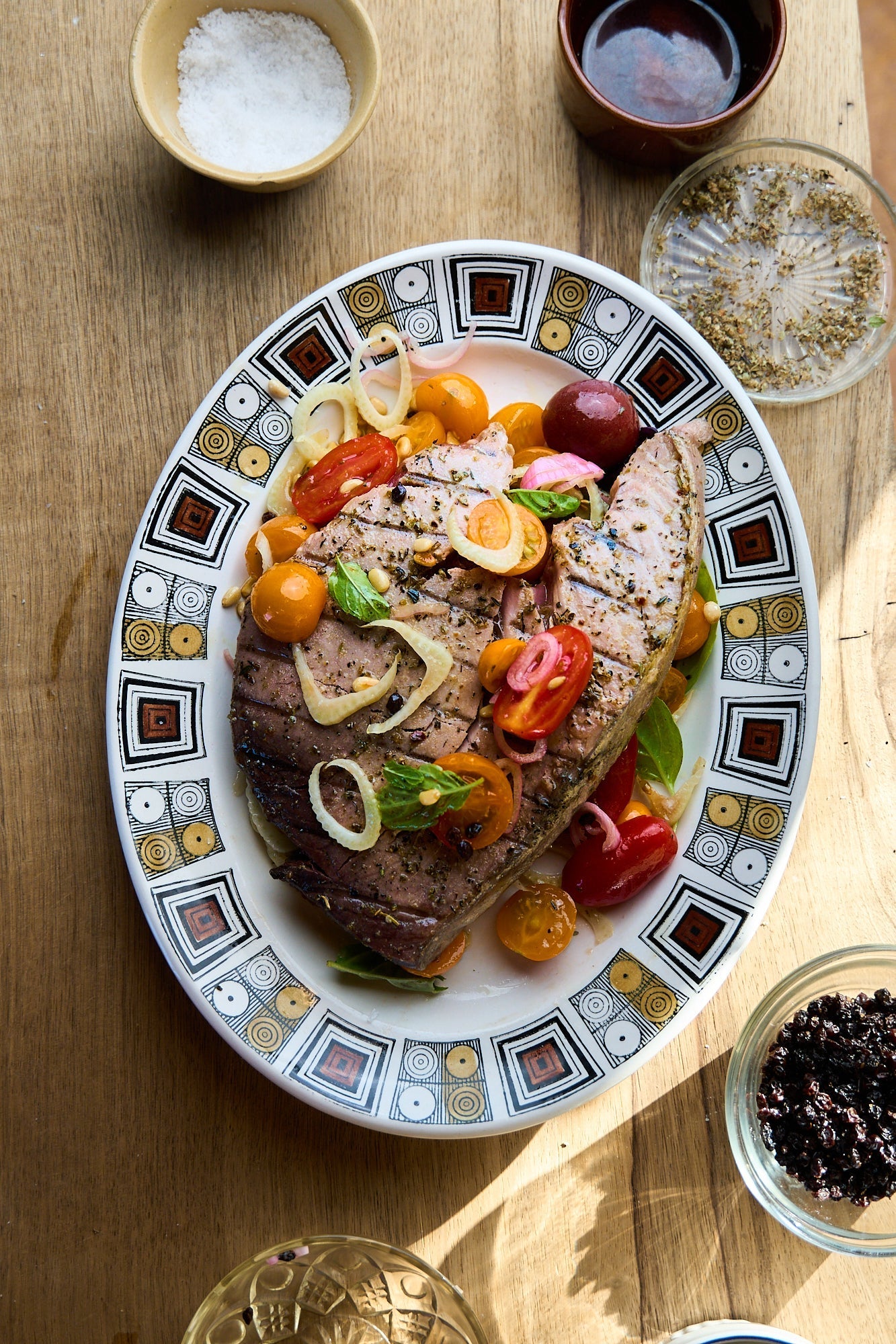 Grilled steak on a decorative plate, garnished with yellow and orange cherry tomatoes.