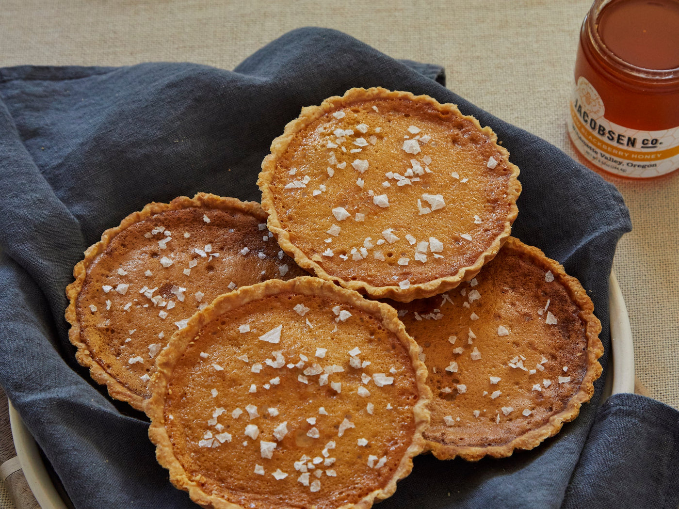 Four salted honey tarts and a jar of honey.