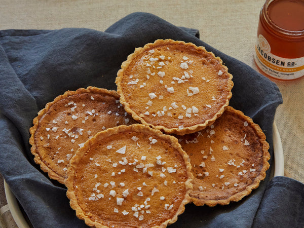 Four salted honey tarts and a jar of honey.