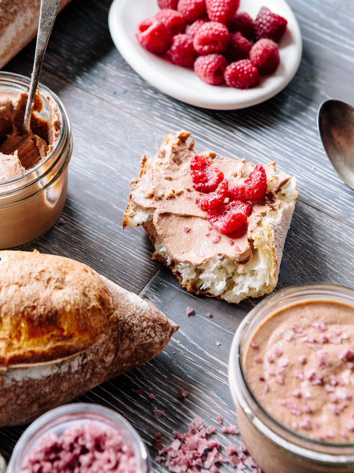 A slice of bread covered with light pink topping and raspberries.
