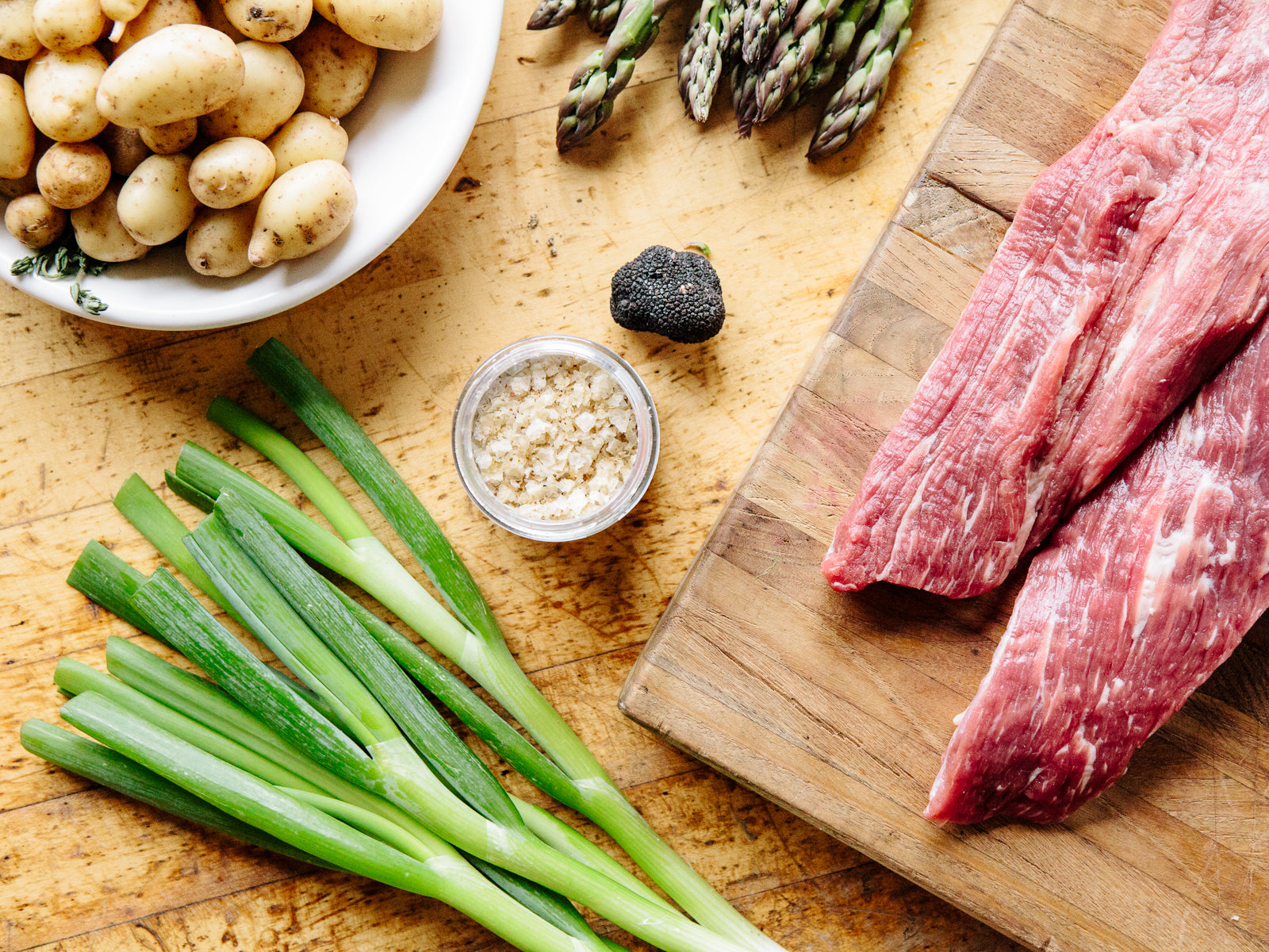 Ingredients on countertop, including raw beef, potatoes and green onions