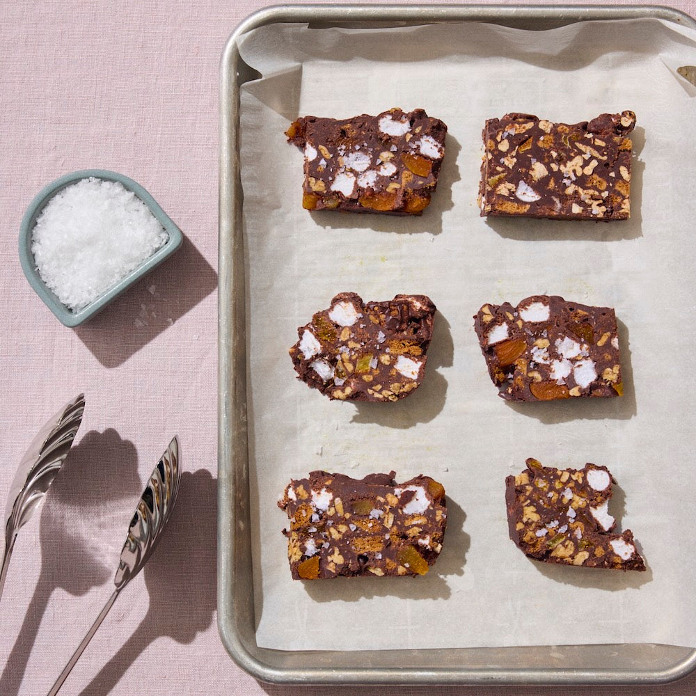 A tray of six rocky roads bars and a salt cellar filled with flakey sea salt.