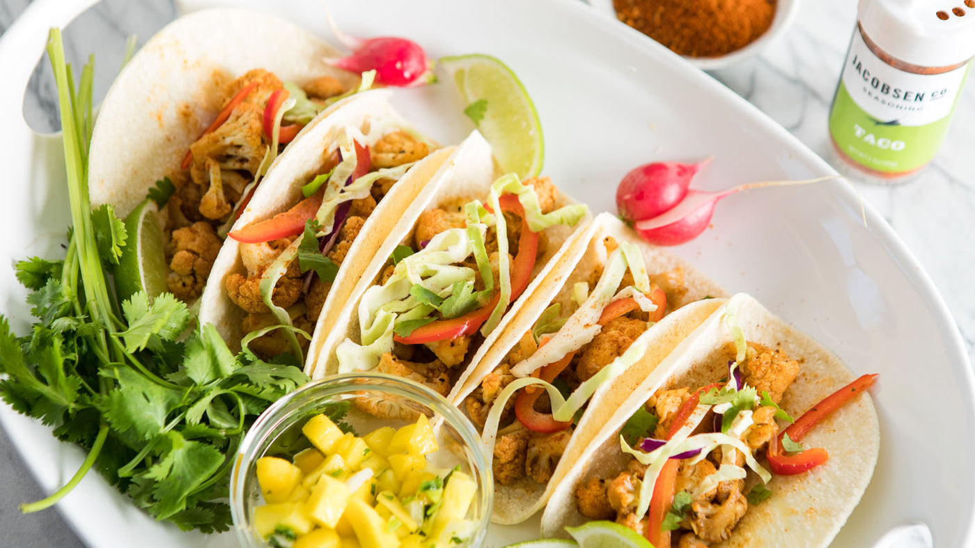A plate with five tacos, filled with seasoned cauliflower.
