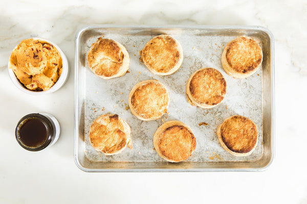A tray of eight biscuits, with a jar of honey butter off to the side.