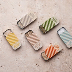Jacobsen Slide tins of various flavors, each open on a countertop showing the infused salts within