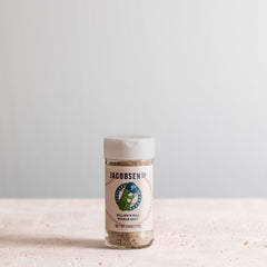 A jar of Dillon's Dill Pickle Salt, a collaboration between Jacobsen Salt Co. and the Portland Pickles baseball team. The label features a cartoon image of a smiling pickle wearing a blue baseball cap. 