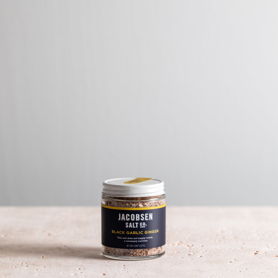 A 2.6 oz jar of Jacobsen Infused Black Garlic Ginger Salt.