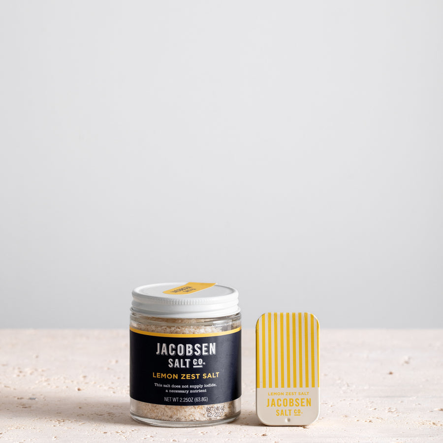 A jar of Jacobsen Infused Lemon Zest Salt next to a matching slide tin of the same product. 