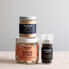 Jacobsen Salt Co bundle, including a jar of Garlic Salt, a jar of Disco di Sale and a grinder of Tellicherry peppercorns.