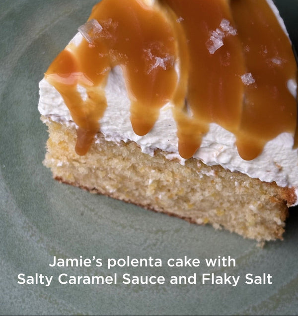 Slice of polenta cake with caramel sauce and flaky salt on a green plate