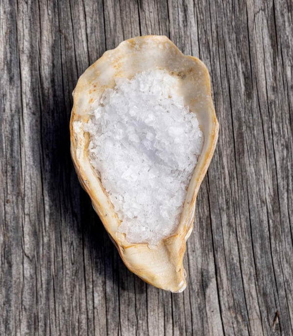Oyster shell filled with salt on a wooden surface