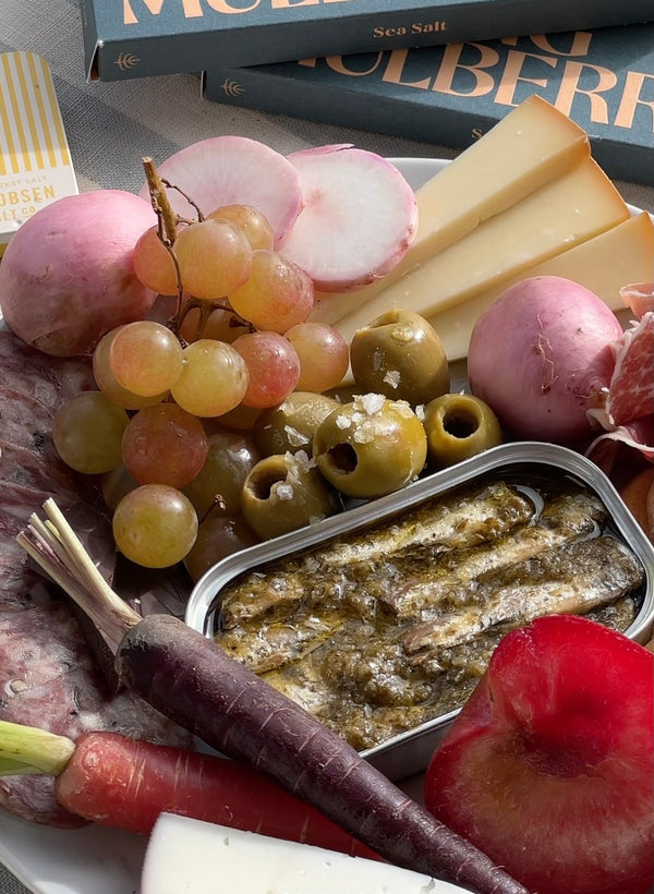 Assorted fruits, vegetables, and cheese on a plate with sea salt